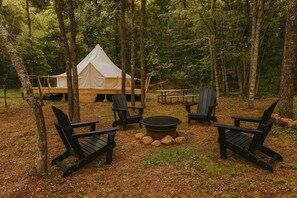 A forest campsite with a tent, Adirondack chairs, a fire pit, and picnic tables. - Wandering Willow – Private Stargazing Glamping Tent with Fire Pit & Open Skies (Bunker)