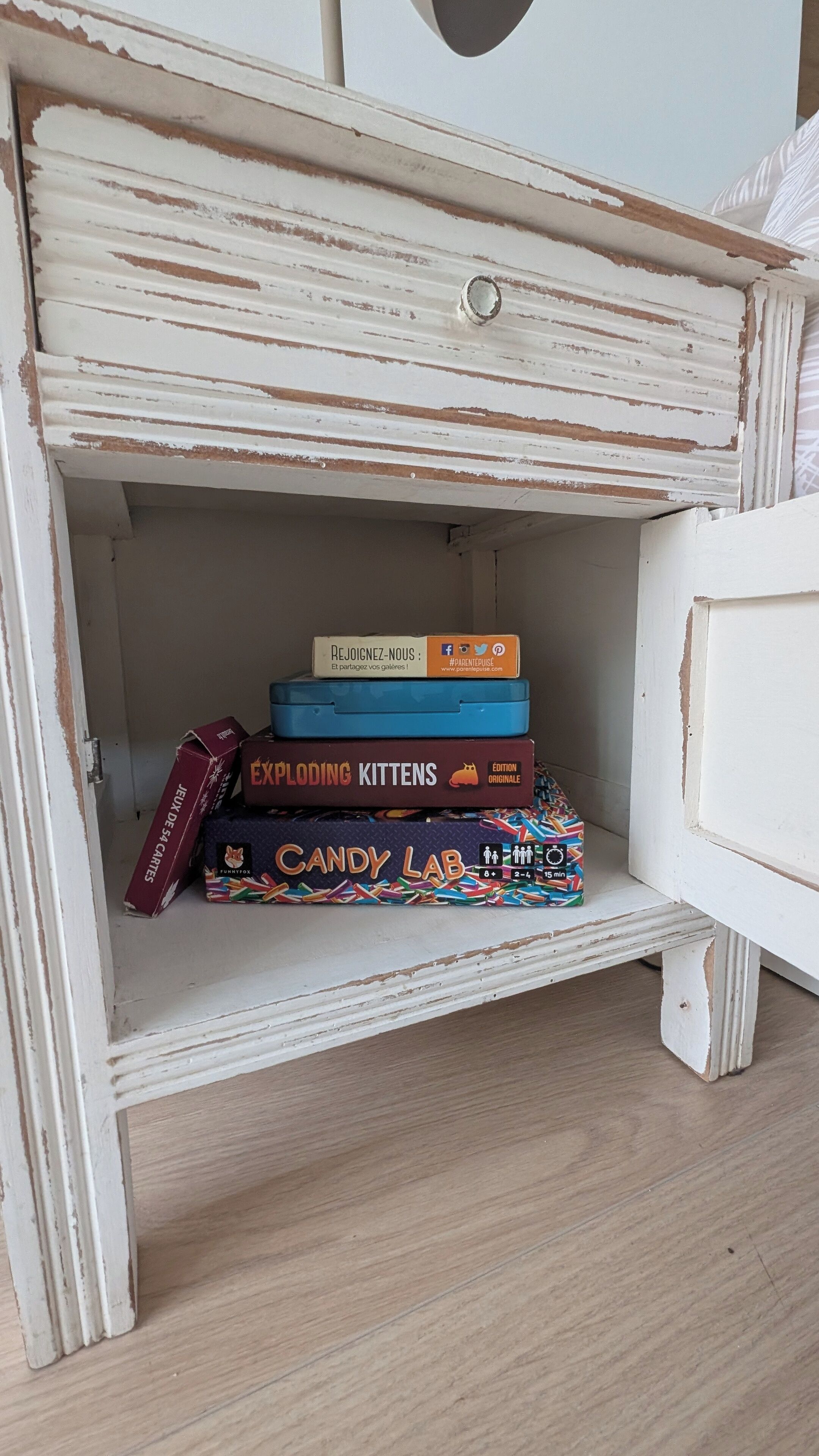 A white dresser with a drawer containing a stack of colorful boxes.