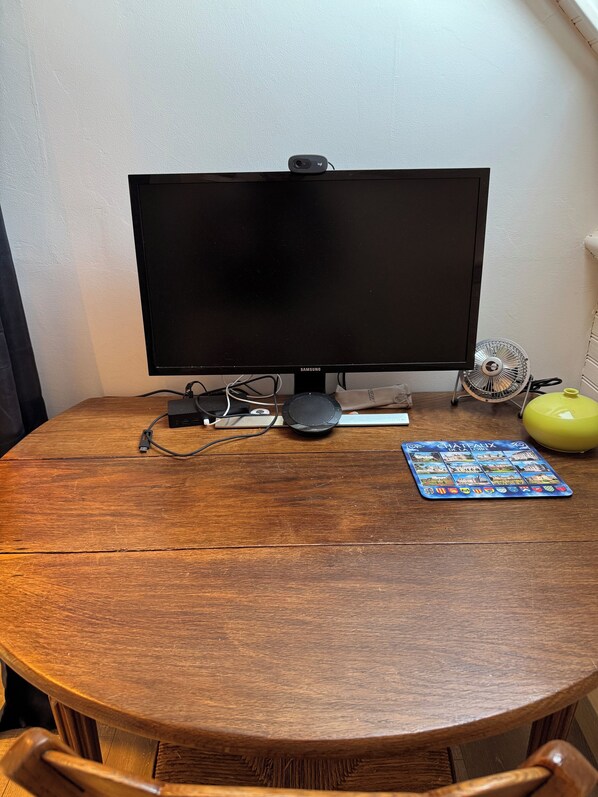 A round wooden table with a black monitor, a speaker, and a game board. - Detached 3-bedroom house, 100 square meters, with a fenced-in yard (Fort-Mahon-Plage)