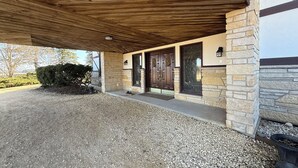 Una entrada cubierta con fachada de piedra, techo de madera y camino de entrada de grava.