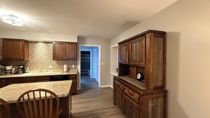 Una cocina con armarios de madera, encimera de granito y comedor con mesa y sillas de madera.