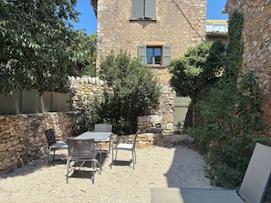 A stone building with a gravel patio, outdoor seating, and a small tree.