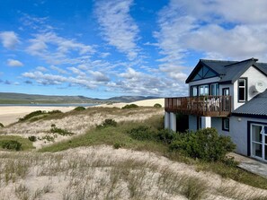 Ein modernes Haus mit Balkon mit Blick auf Strand und Dünen.
