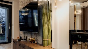 Uma cozinha moderna com uma televisão grande, armários de madeira e bancada de mármore.