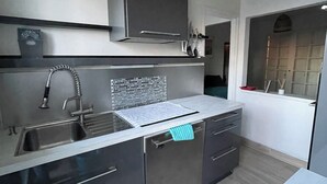 A modern kitchen with a stainless steel sink, a built-in oven, and a dishwasher. - Vacation home, Villa Hortense (Notre-Dame-de-Monts)
