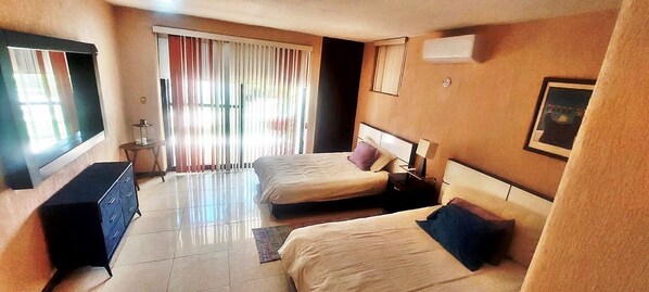 A hotel room with two beds, a dresser, a mirror, and a window with curtains.