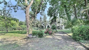 A park with trees, a grassy area, and a pathway. - Le Grand Kergroas - LANNEBERT (LANNEBERT)