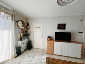 A modern living room with a TV, a white door, and a mirror on the wall. - T2 Cabin Apartment - Balcony Near Beach - Sleeps 4 (Argelès-sur-Mer)