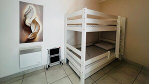 A bunk bed room with a radiator, a poster, and a hanging light fixture.