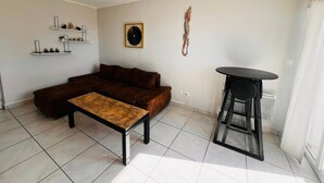 A living room with a sectional sofa, a coffee table, a round table, and a ceiling fan.