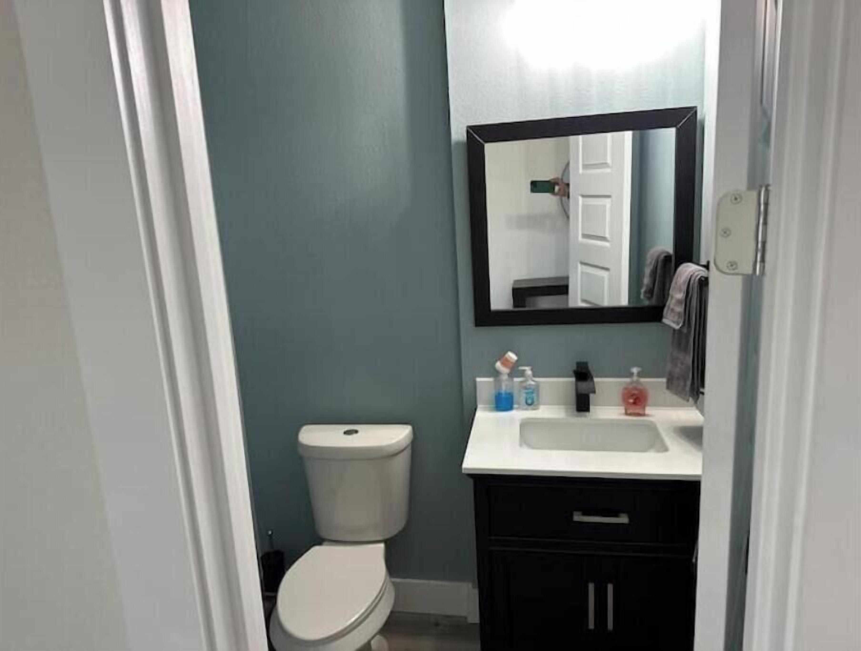 A bathroom with a toilet, a sink, a mirror, and a towel hanging on the wall.