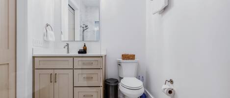 Un baño moderno con tocador blanco, inodoro y cubo de basura.