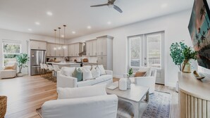 A modern kitchen with white cabinets, a stainless steel refrigerator, and pendant lighting. - New! Alora: Gorgeous 4BR Beach Getaway w Game Room + Spa + Firepit (Santa rosa beach)