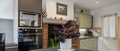A modern kitchen with a brick fireplace, a built-in oven, and a dining area with a black table.