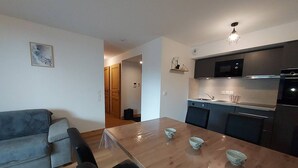 A modern kitchen with a dining table, chairs, and a microwave. There is a sofa in the living area and a door leading to another room. - Cozy apartment 6 pers, ski-in access, parking included (Valmorel)