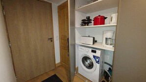 A compact laundry room with a washing machine, a dryer, a coffee maker, and a red pot on the shelf. - Cozy apartment 6 pers, ski-in access, parking included (Valmorel)