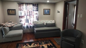 A living room with two sofas, a rug, and a door leading to another room. - Charming 2-bedroom cabin in Big Clifty with WiFi, AC (Big Clifty)