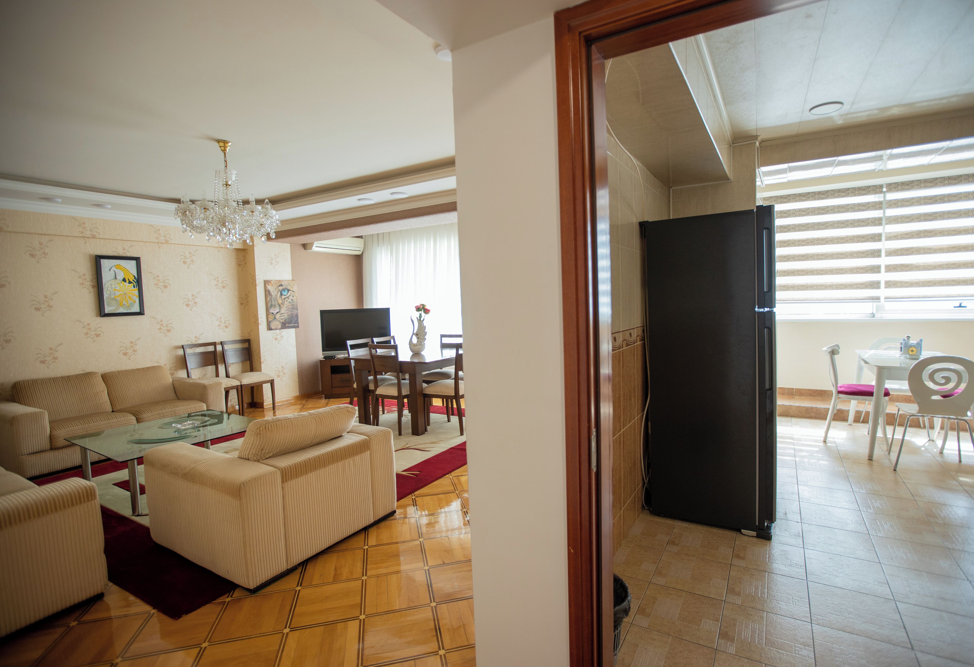 Una sala de estar con un sofá, un sillón y una mesa de centro de vidrio. Hay un comedor con una mesa y sillas.