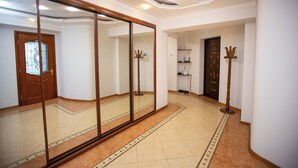 Un pasillo con un espejo grande, una puerta de madera y un perchero.