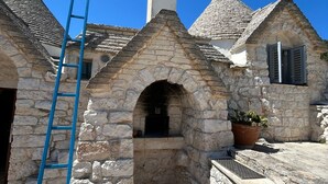 A stone building with a central arched structure, a chimney, and a blue ladder. - 15' to Monopoli, 10' to Capitolo Sea, 10/20' to all places in Valle D'Itria (Puglia)