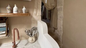 A bathroom with a stone sink, a copper faucet, and a shelf with decorative items. - 15' to Monopoli, 10' to Capitolo Sea, 10/20' to all places in Valle D'Itria (Puglia)