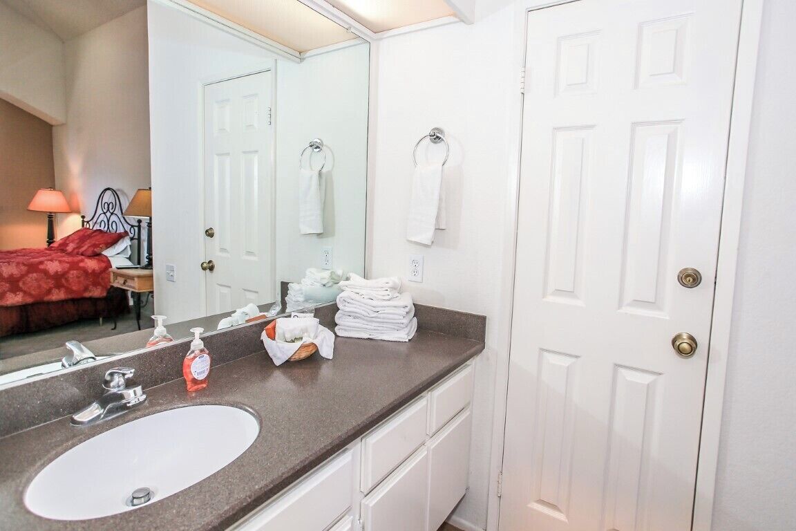 A bathroom with a white sink, mirror, and towel rack.