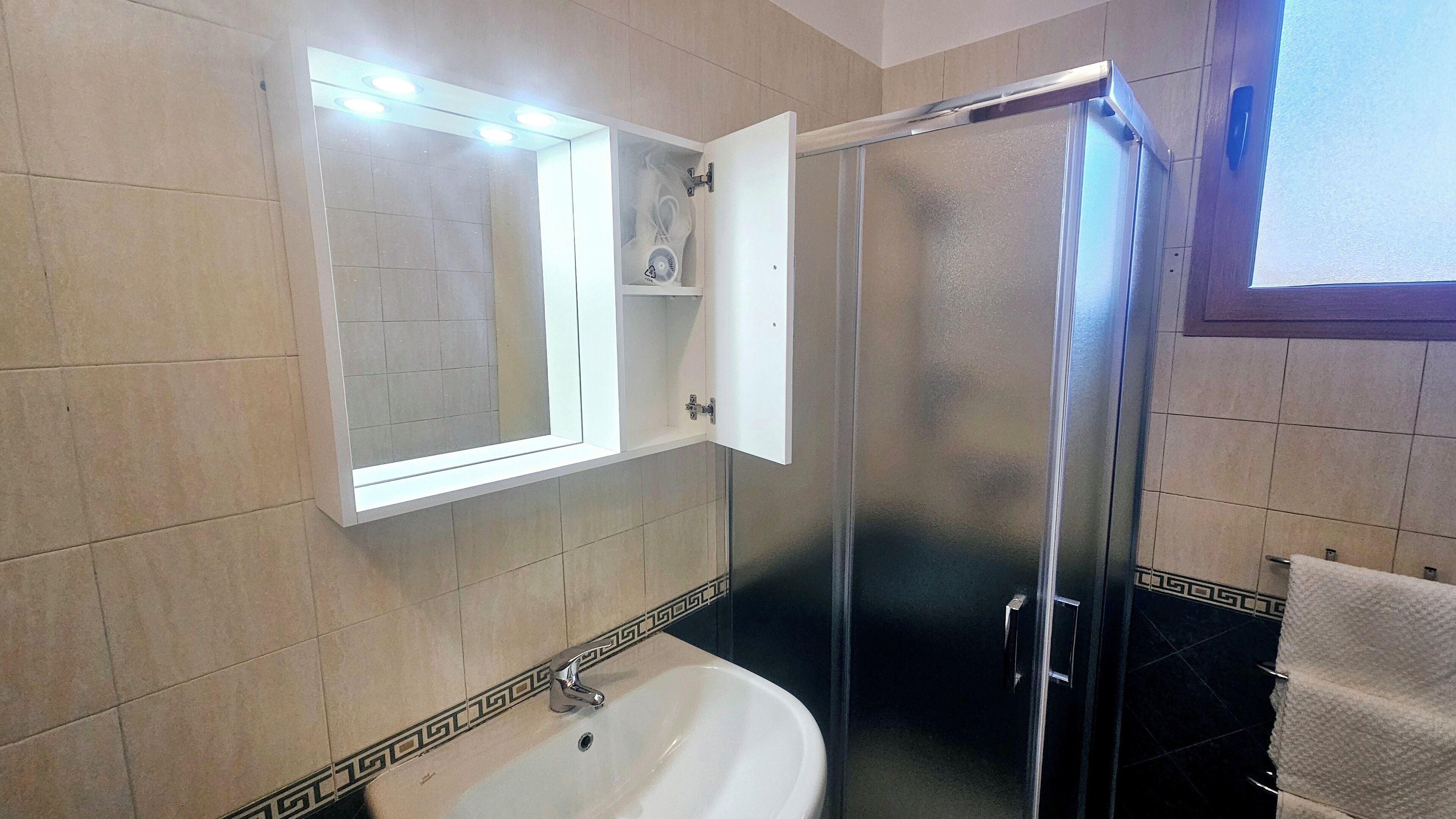 Un bagno con lavandino bianco, specchio e cabina doccia.