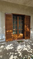 Una puerta de madera con paneles de vidrio, un banco blanco y un felpudo en un área empedrada con piedra.