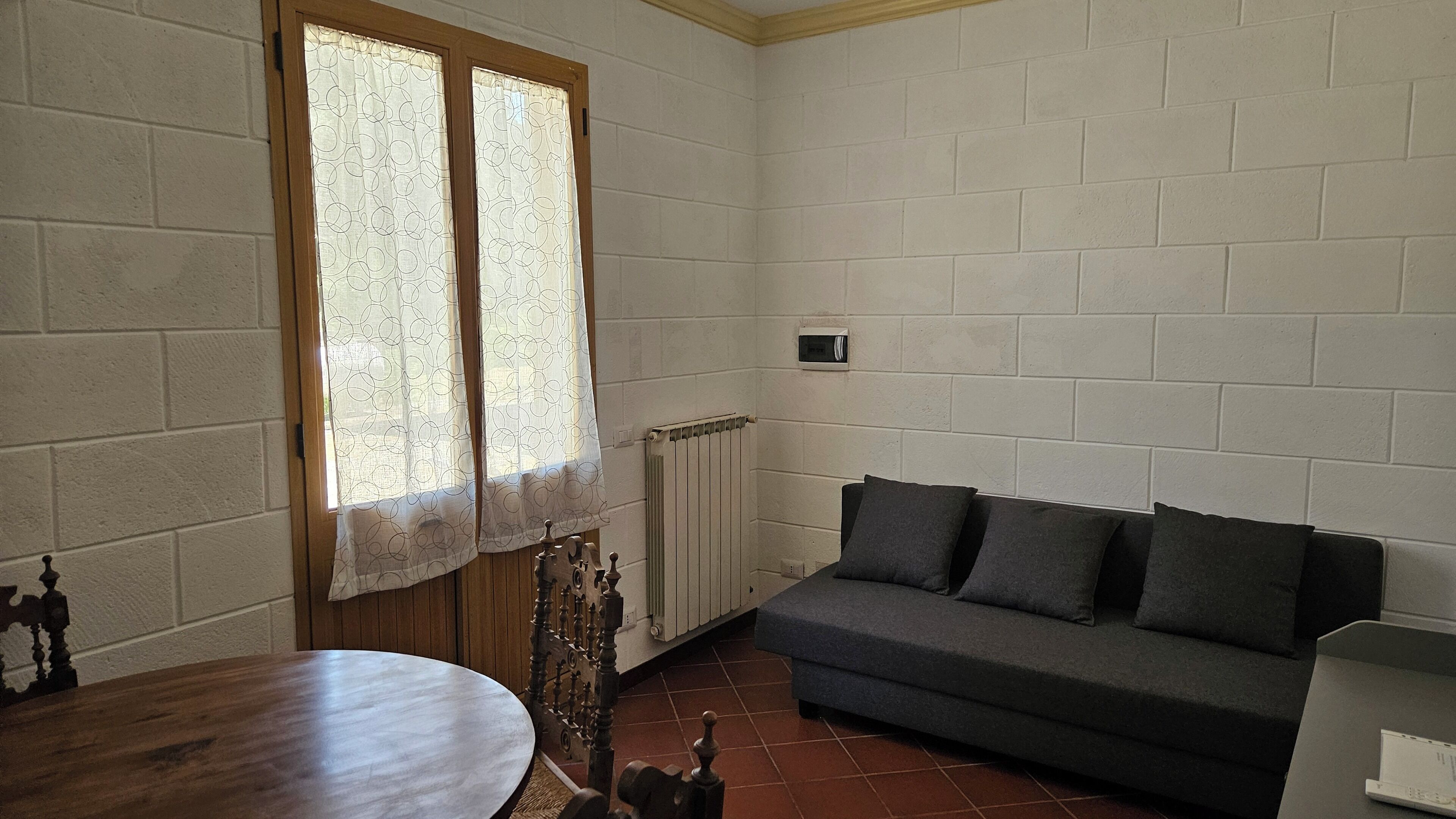 A room with a wooden table, a sofa, and a radiator.