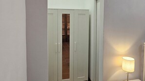 A hallway with a white door, a small table with a lamp, and an air conditioning unit on the wall. - La Pineta (Lecce)