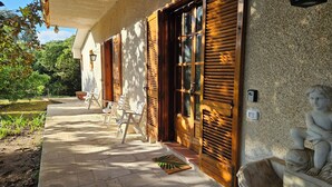 A building with wooden shutters, a stone pathway, outdoor seating, and a statue. - La Pineta (Lecce)