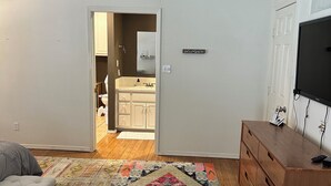 A bedroom with a bed, a wooden dresser, a television, and a patterned rug. - Charming 3-bedroom house in tranquil Cloudcroft with WiFi (Cloudcroft)