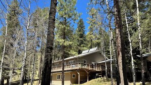 A two-story house with a balcony, surrounded by tall trees and a clear blue sky. - Charming 3-bedroom house in tranquil Cloudcroft with WiFi (Cloudcroft)