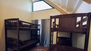 A room with two bunk beds, a small rug, and a window with curtains.