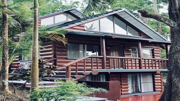 A two-story wooden cabin with a balcony and a staircase leading to the entrance.