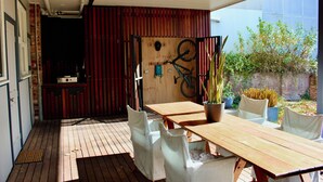 A wooden deck with a table and chairs, a bicycle mounted on the wall, and a potted plant. - Convenient & Cosy Mountain Retreat in Omeo. (Omeo)