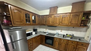 Una cocina con gabinetes de madera, un refrigerador de acero inoxidable, un microondas, una estufa y un lavamanos.