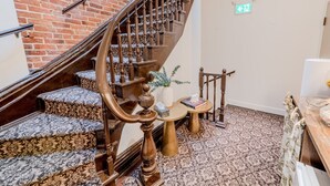 Una escalera con barandillas de madera decoradas y piso alfombrado.