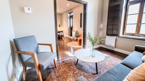 A modern living room with a grey sofa, a round coffee table, and a large mirror.