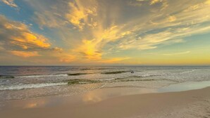 Uma praia com ondas e um céu ao pôr do sol.