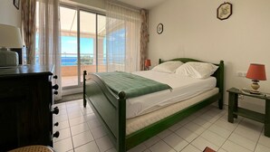 A bedroom with a bed, a desk, a chair, a lamp, a window with curtains, and a view of the sea. - Spacious 80m² apartment with pool and sea view in Sète (Sète)
