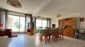 A spacious living room with a dining area, large windows, and a view of the outdoors. - Spacious 80m² apartment with pool and sea view in Sète (Sète)