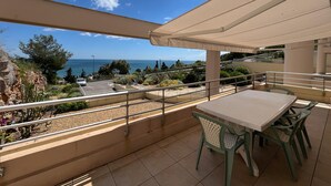 A balcony with a table and chairs, overlooking a coastal view with the sea and greenery. - Spacious 80m² apartment with pool and sea view in Sète (Sète)