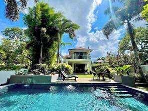 Una casa de dos pisos con una piscina delantera.