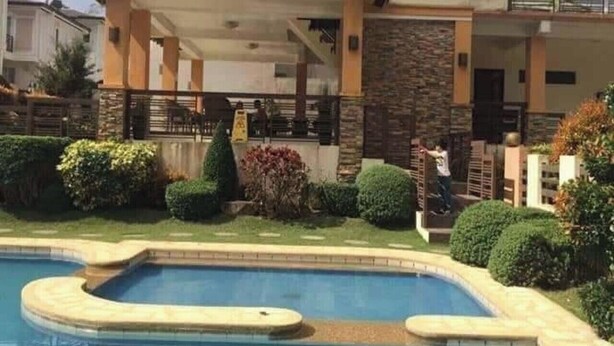 A residential property with a swimming pool, a covered patio, and a stone facade.