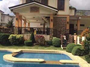 Une propriété résidentielle dotée d’une piscine, d’un patio couvert et d’une façade en pierre.