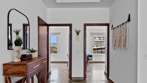 A modern hallway with a wooden console table, a mirror, and a plant. There are two doors leading to other rooms. - Cozy 2BR in Versalles – Walk to Beach & Dining (Puerto Vallarta)