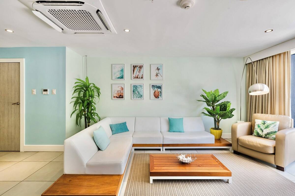 A modern living room with a white sofa, a wooden coffee table, and two potted plants.