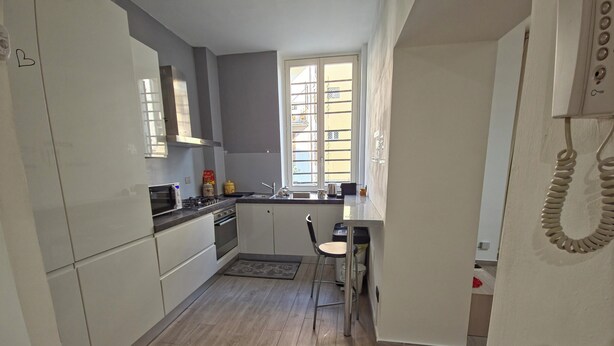 A compact kitchen with white cabinets, a stove, and a sink. - Central and quiet apartment, 1 min from the Duomo and 3 min from Lake Como. (Como)
