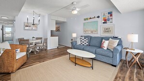 A modern living room with a blue sofa, wicker chair, and a white coffee table.